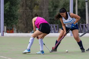 Intense game of field hockey with two women competing on an outdoor court. jigsaw puzzle