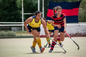 Two women playing field hockey outdoors, showcasing intense competition and teamwork. jigsaw puzzle