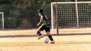 A soccer player dribbles the ball on a dry soccer field in daytime during a match. jigsaw puzzle