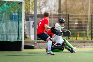 Intense moment in a field hockey match as a goalkeeper blocks a shot near the goal post outdoors. jigsaw puzzle