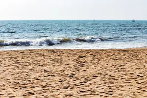 A peaceful sandy beach with gentle ocean waves under a clear sky. jigsaw puzzle