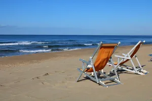 Two empty deck chairs on a sandy beach under clear blue skies in Latina, Italy. jigsaw puzzle