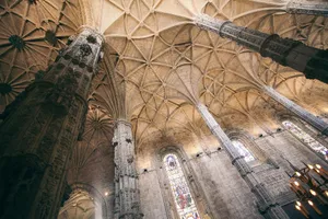 From below of ornamental ceiling over huge columns against brick walls with stained glass jigsaw puzzle