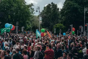 Large crowd gathered for an outdoor celebration with balloons and flags, enjoying a lively festival atmosphere. jigsaw puzzle
