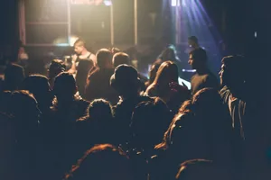 A lively crowd enjoying a concert with soft lighting and performers on stage. jigsaw puzzle