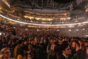 A large crowd gathers in an indoor arena for a lively event, surrounded by bright lights. jigsaw puzzle