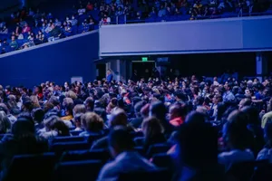 A crowded conference hall with diverse audience attentively listening to a speaker. jigsaw puzzle