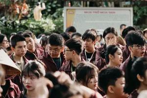 A large group of young adults socializing outdoors, wearing matching attire. jigsaw puzzle