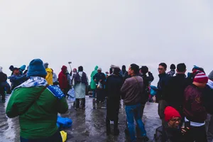 A group of tourists dressed warmly in winter clothing, gathering on a foggy day. jigsaw puzzle