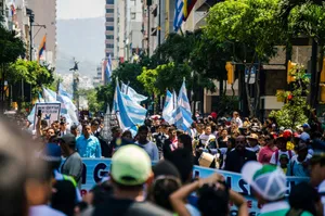 A lively urban protest with people holding flags and signs on a sunny day. jigsaw puzzle