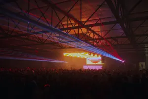 A lively indoor concert featuring colorful laser lights over a large crowd enjoying music. jigsaw puzzle