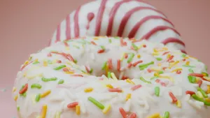 Close-up of delicious white icing donuts with colorful sprinkles and a pink background. jigsaw puzzle