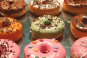 A close-up of various colorful iced donuts topped with chocolate sprinkles on a reflective surface. jigsaw puzzle