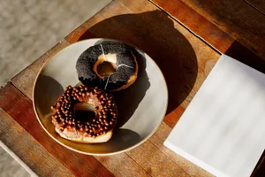 Two donuts with chocolate and glaze toppings served on a plate, ideal for breakfast. jigsaw puzzle