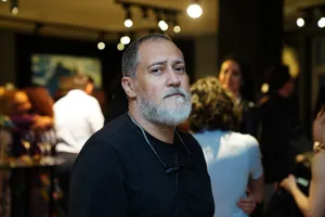 Bearded man gazing at camera in lively indoor setting with group of people. jigsaw puzzle