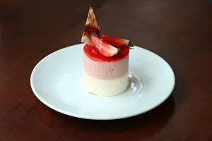 Delicious layered strawberry mousse dessert with fresh fruit topping served elegantly on a white plate. jigsaw puzzle