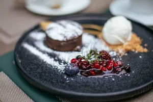 Close-up of a gourmet dessert with chocolate, berries, and ice cream on a black plate. jigsaw puzzle