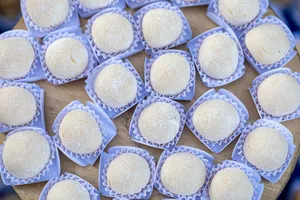 A close-up view of traditional Brazilian Beijinho coconut sweets displayed in blue wrappers. jigsaw puzzle