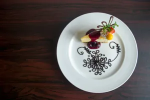 Exquisite plated dessert with artistic chocolate design and fruit garnish on a white plate. jigsaw puzzle