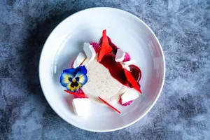 Elegant gourmet dessert with vibrant edible flowers and garnishes, artistically presented on a white plate. jigsaw puzzle