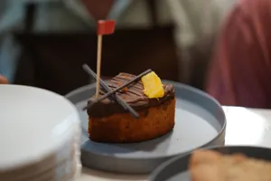 Close-up of a chocolate orange cake with flag decoration, served on a blue plate. jigsaw puzzle