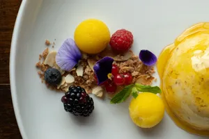 A beautifully plated dessert with mango sorbet, fresh berries, and edible flowers. jigsaw puzzle