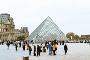 Tourists gather around the iconic Louvre Pyramid in Paris, highlighting European architecture. jigsaw puzzle