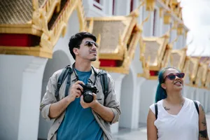 Two tourists with cameras enjoy a sunny day at an ornate Asian temple. jigsaw puzzle