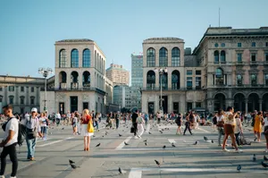 Bustling scene at Milan's Museo del Novecento with visitors and pigeons under a clear sky. jigsaw puzzle