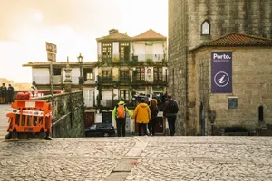 Group of people walking down cobblestone streets in Porto, Portugal, showcasing historic architecture. jigsaw puzzle