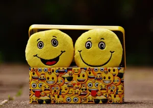 Two yellow smiley plush toys in an emoji-themed box, expressing fun and happiness. jigsaw puzzle