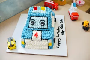 Decorative birthday cake in the shape of a cartoon police car surrounded by toy vehicles on a table. jigsaw puzzle