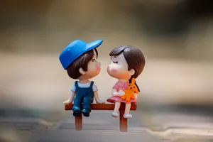 Tiny figurine of cute little girl and boy sitting on bench together and kissing jigsaw puzzle