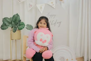 Happy girl hugging a pink stuffed toy at a birthday celebration indoors. jigsaw puzzle