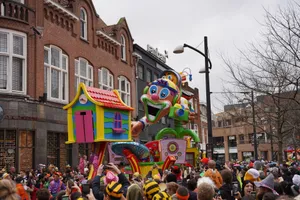 Lively street festival in Holland featuring colorful floats and a joyful crowd under cloudy skies. jigsaw puzzle
