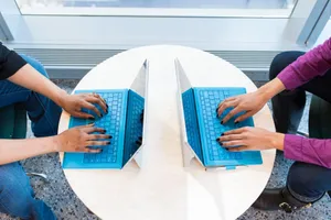 Two people working on blue laptops at a round table, focusing on teamwork and technology. jigsaw puzzle
