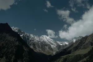 Stunning view of snow-capped mountains under a clear blue sky with scattered clouds. jigsaw puzzle