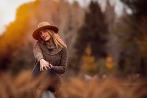 A vibrant autumn portrait of a smiling woman in a hat, enjoying the outdoors in a knitted sweater. jigsaw puzzle