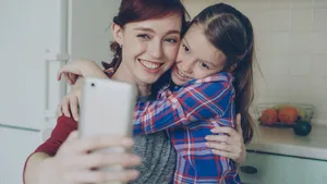 Smiling mother and daughter taking a selfie in a cozy indoor setting. jigsaw puzzle