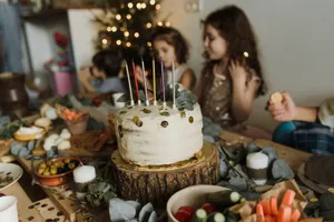 A festive birthday scene with children, cake, and decorations indoors. jigsaw puzzle