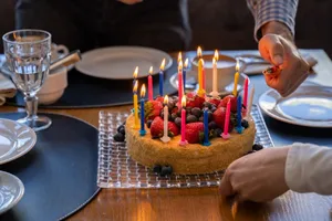 A vibrant birthday cake adorned with candles and berries, set for celebration indoors. jigsaw puzzle