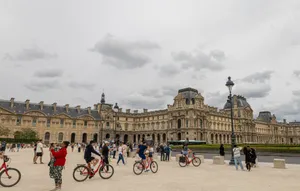 Tourists and bicyclists enjoy a day at the iconic Louvre Museum in Paris. jigsaw puzzle