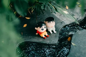 Two cartoon figurines sit on a stone ledge near a lush garden stream. jigsaw puzzle