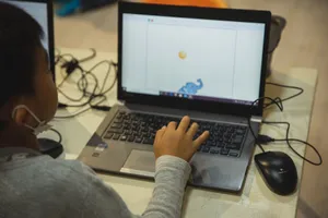 From above back view of crop anonymous Asian schoolchild typing on netbook with illustration on screen during lesson in school jigsaw puzzle