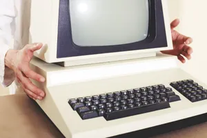 A vintage computer with a classic CRT monitor and keyboard, being held by hands. jigsaw puzzle