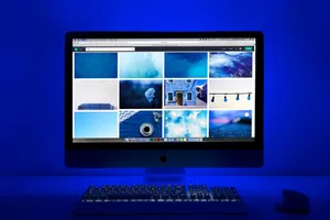 Modern workspace with a glowing blue theme and a computer monitor showcasing a gallery of images. jigsaw puzzle