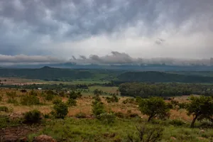 Expansive rural landscape with rolling hills under dramatic cloudy sky, conveying tranquility and remoteness. jigsaw puzzle