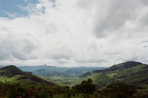 Picturesque landscape of vast hilly valley covered with abundant green plants under cloudy sky jigsaw puzzle