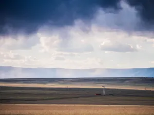 Expansive view of New Mexico plains under a dramatic cloudy sky featuring a lone windmill. jigsaw puzzle