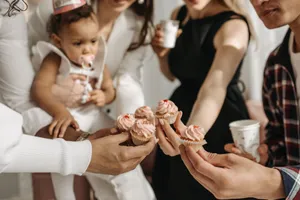 A joyful celebration with a baby girl and cupcakes, surrounded by friends. jigsaw puzzle